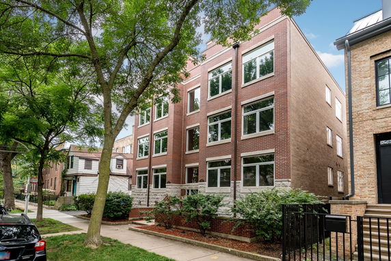 Front view of a multi-story brick building with large windows.