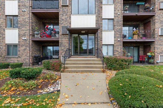 Front view of a multi-story brick apartment building with balconies.