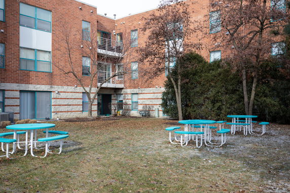 Rear view of a multi-story brick building with outdoor seating area.
