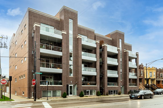 Front view of a modern multi-story brick apartment building with balconies.