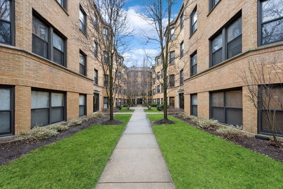 Front view of a multi-story brick apartment complex with a central walkway.
