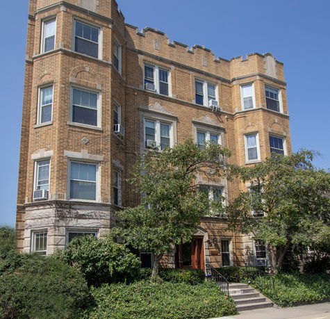 Front view of a multi-story brick apartment building with decorative stonework and several windows.