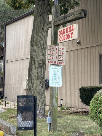 Elevation view of a building structure with a wooden exterior and a signpost reading 'Oak Hill Colony'.