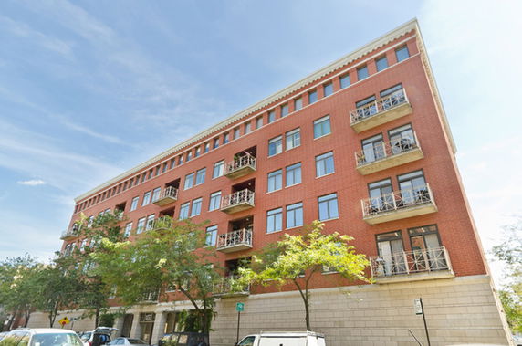 Front view of a multi-story brick apartment building with balconies.