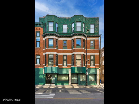 Front view of a multi-story building with red brick and green detailing.