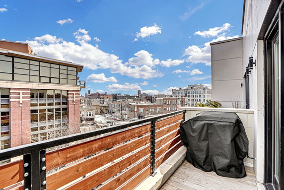 Panoramic view from a balcony overlooking surrounding buildings on a clear, sunny day.