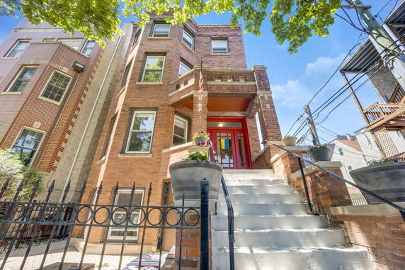 Front view of a multi-story brick house with red entrance.
