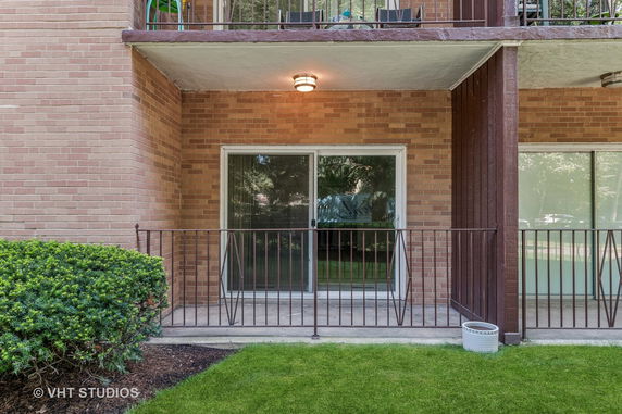 Front view of a building with brick exterior and balcony with sliding glass door.