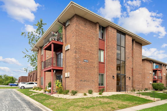 Front view of a multi-story apartment building with brick exterior and balconies.