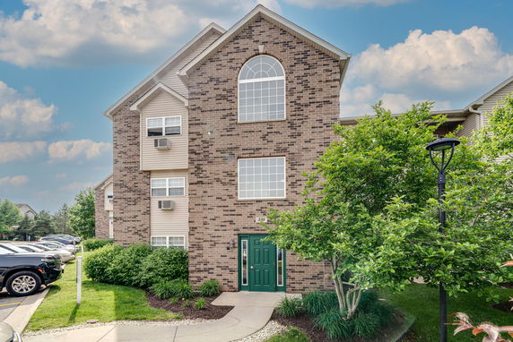 Front view of a multi-story brick residential building with arched window and green door.