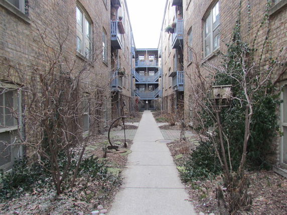 Pathway between two brick residential buildings with balconies.