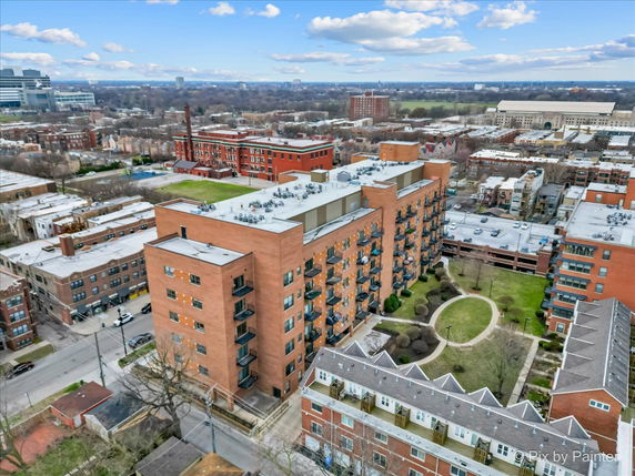 Aerial view of a large brick apartment building with visible rooftops featuring various equipment.