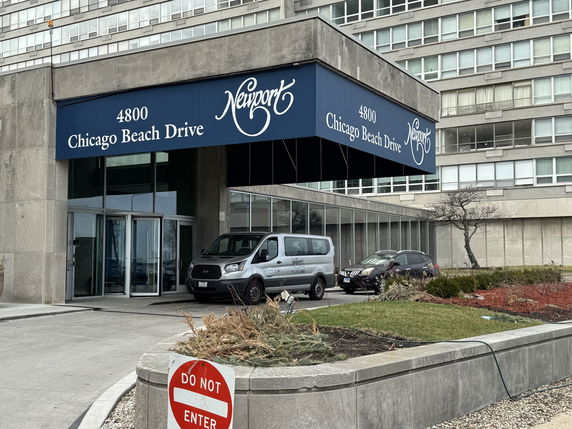 Front view of a multi-story building with a glass entrance and awning featuring address signage.
