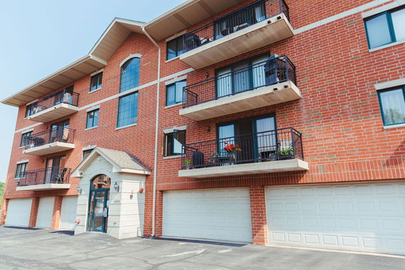 Front view of a multi-story brick apartment building with multiple balconies.