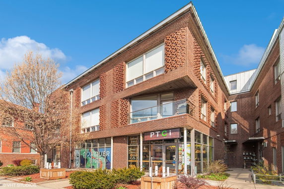 Front view of a modern three-story brick building with large windows and a glass doorway.