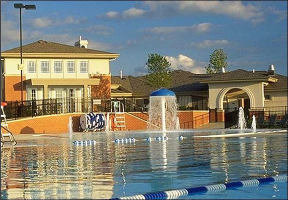 Outdoor swimming pool area with fountains in front of a building.