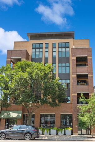 Front view of a multi-story building with large windows and brick facade.