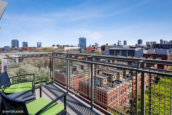 Panoramic view from a balcony over a cityscape with buildings and clear blue sky.