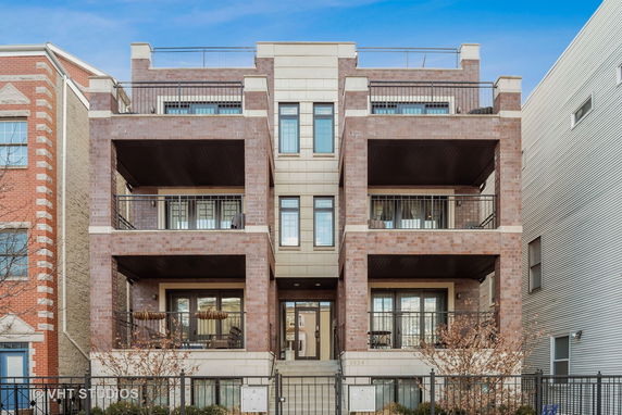 Front view of a multi-story brick apartment building with balconies.