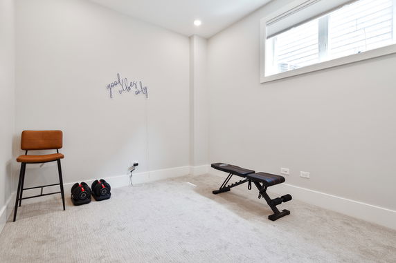 Room with exercise bench, weights, and a chair.