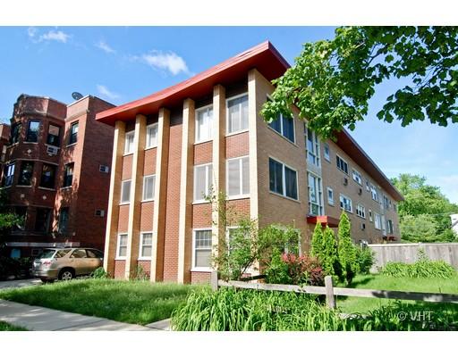 Front view of a multi-story residential building with a brick facade and distinctive red roof edge.