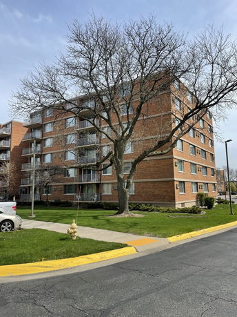 Front view of a multi-story brick apartment building with balconies.