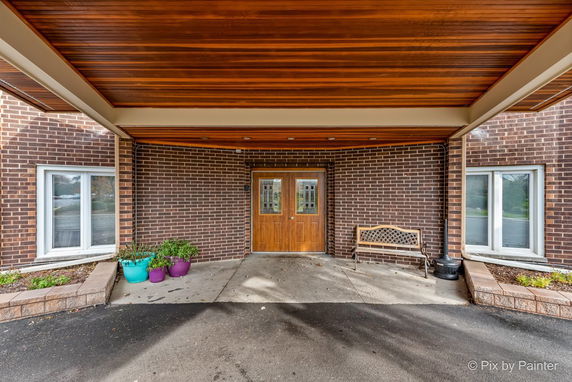 Front entrance of a building with brick walls and wooden double doors.