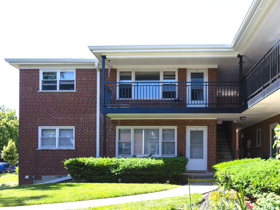 Front view of a two-story brick apartment building with balconies.