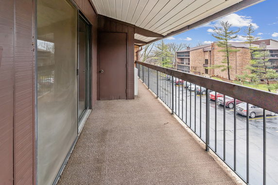 Balcony with a view of a parking area and apartment buildings.
