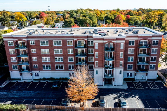 Front view of a multi-story building with balconies and a parking area.