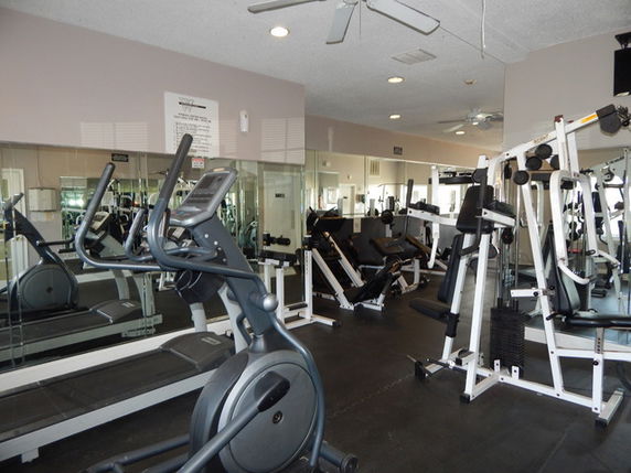 Interior view of a gym with exercise equipment and mirrors.