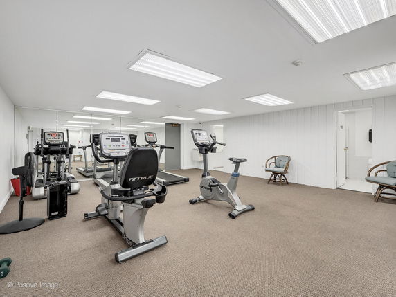 Indoor gym area with exercise equipment and wall mirrors.