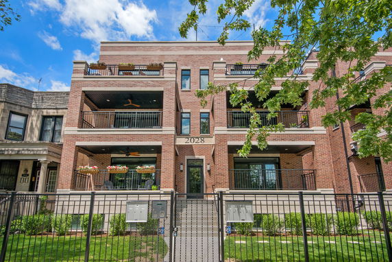 Front view of a multi-story brick apartment building with balconies.