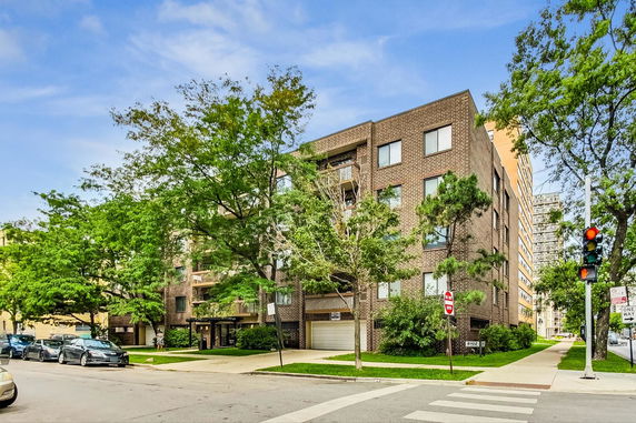 Front view of a multi-story brick building with a street and trees.