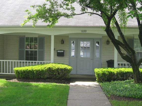 Front view of a house with a covered porch and two front windows.