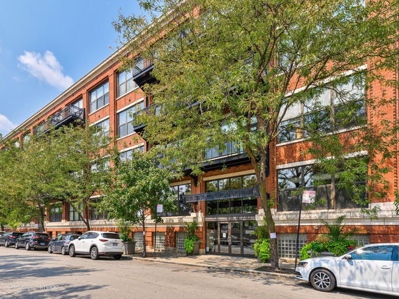 Front view of a multi-story brick building with balconies and large windows.