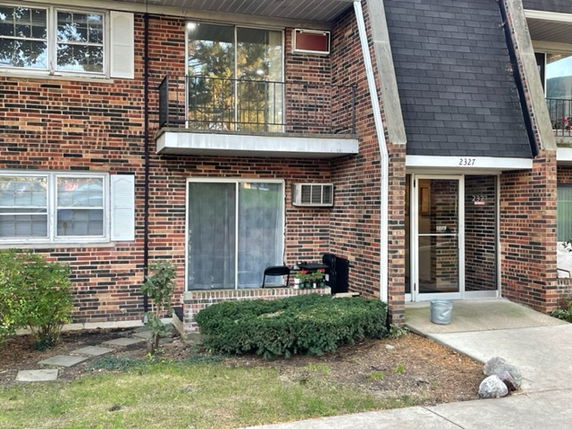 Front view of a brick apartment building with balconies and entrance.