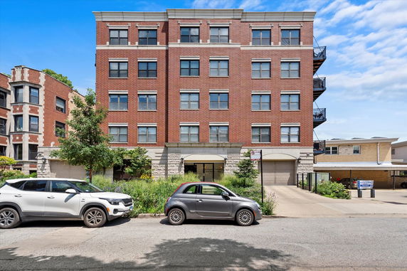 Front view of a multi-story brick building with large windows.