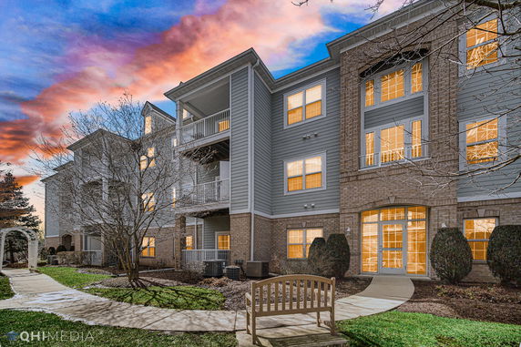 Front view of a multi-story residential building with balconies and a brick facade.