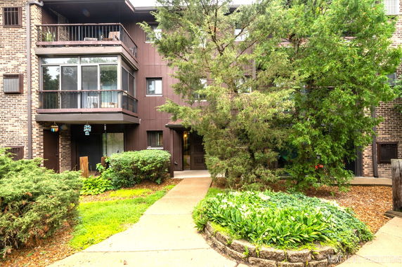 Front view of a multi-story residential building with balconies and a brick facade.