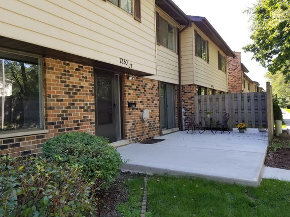 Front view of a townhouse with brick facade and patio area.