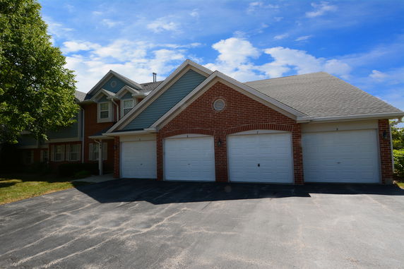 Front view of a two-story house with a brick facade and multiple garages.