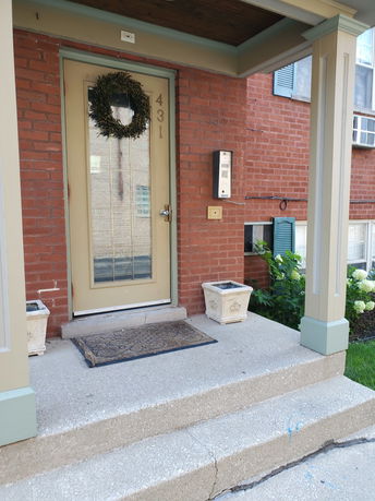 Front entrance of a brick house with a decorated door and steps.