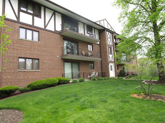 Front view of a multi-story apartment building with a brick facade and balconies.