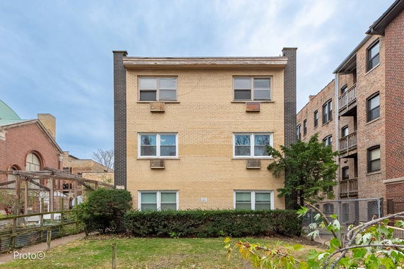Front view of a three-story residential building with multiple windows and brick construction.