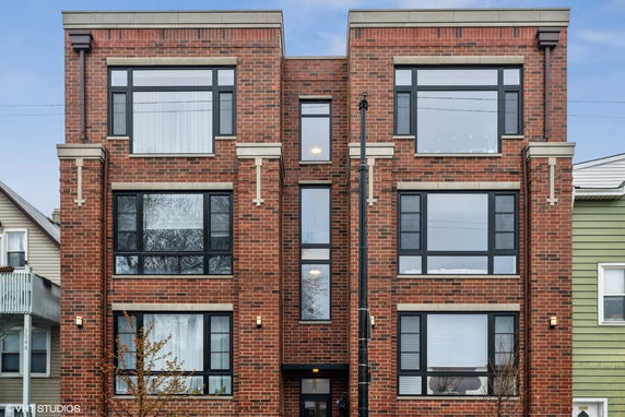 Front view of a multi-story brick building with large windows.
