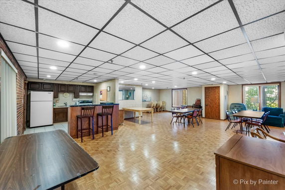 Interior view of a recreation area with a kitchenette, seating, and tables.