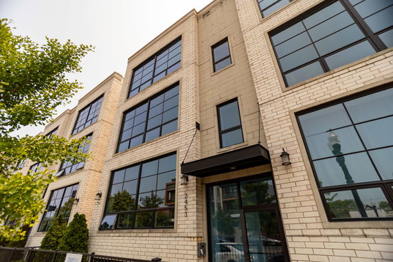 Front view of a modern multi-story building with large windows and brick facade.