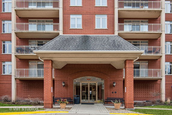Front view of a multi-story brick building with balconies and an entrance canopy.