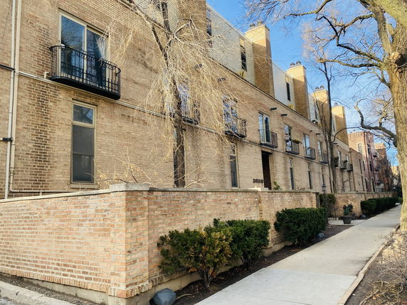 Front view of a multi-story brick building with small balconies.